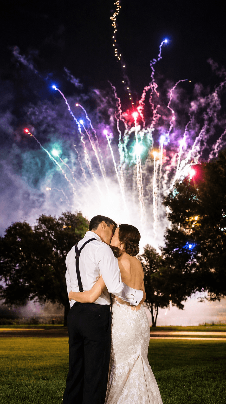 Wedding couple kissing beneath fireworks