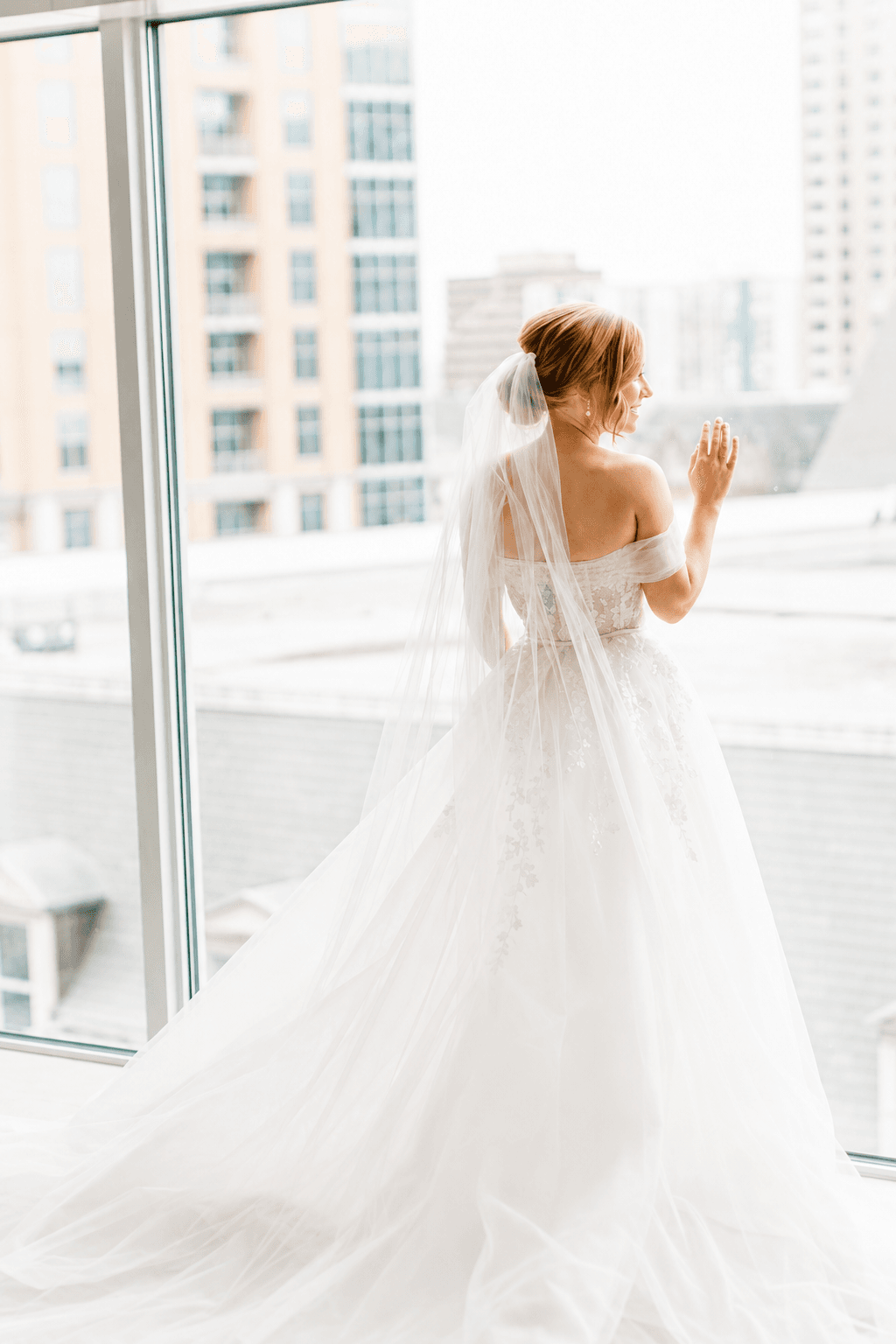 Bride at window with city backdrop