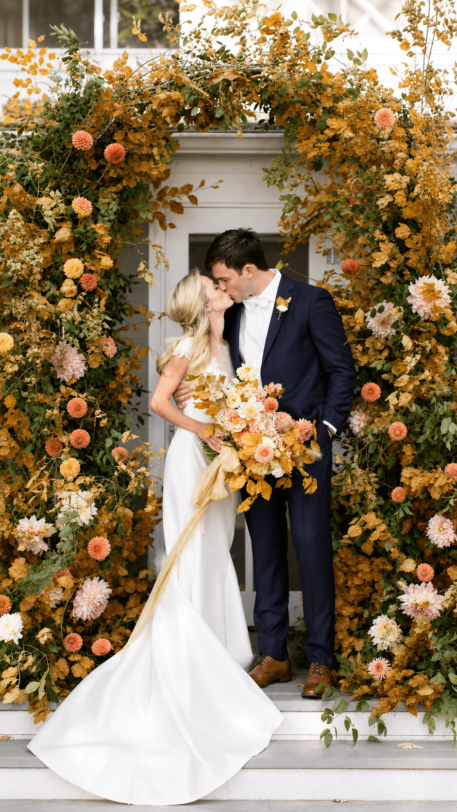 Couple kissing under fall floral arch
