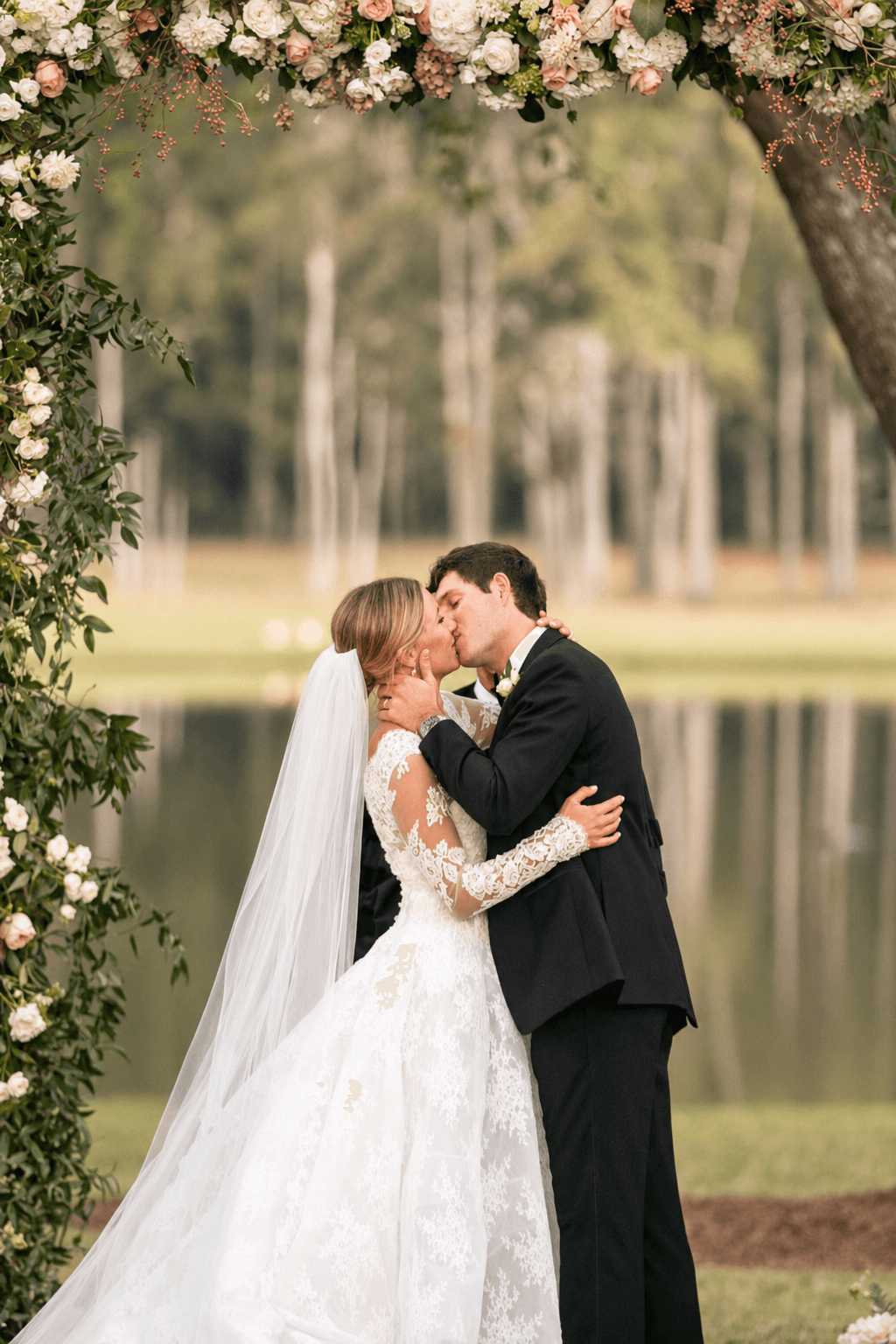 First kiss under lakeside floral arch